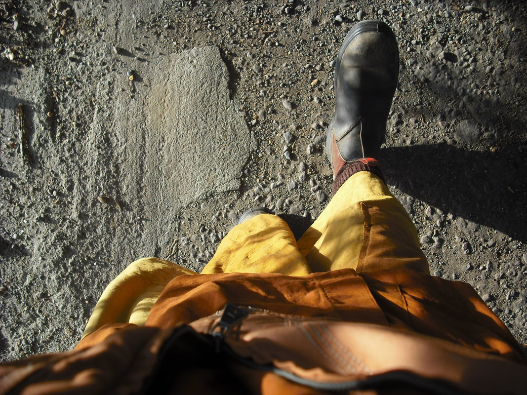 Photo of monk's lower body from above, taking a right step on a gravel road