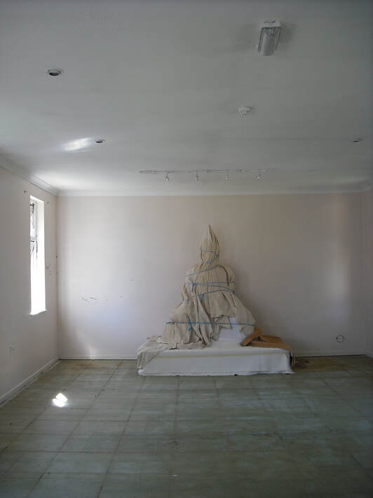 Photo of overcovered Buddha statue in an unfurnished empty room