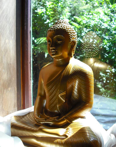 Photo of peaceful brass Buddha statue in a window 